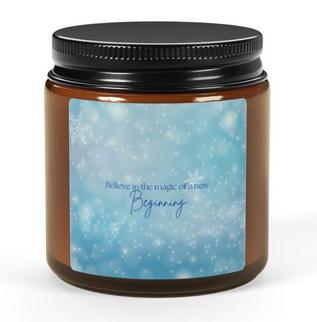 Amber jar candle with a blue label reading, "Believe in the magic of a new beginning." Set on a wooden coaster, surrounded by string lights, a ukulele, and a book, creating a cozy and serene ambiance perfect for relaxation.